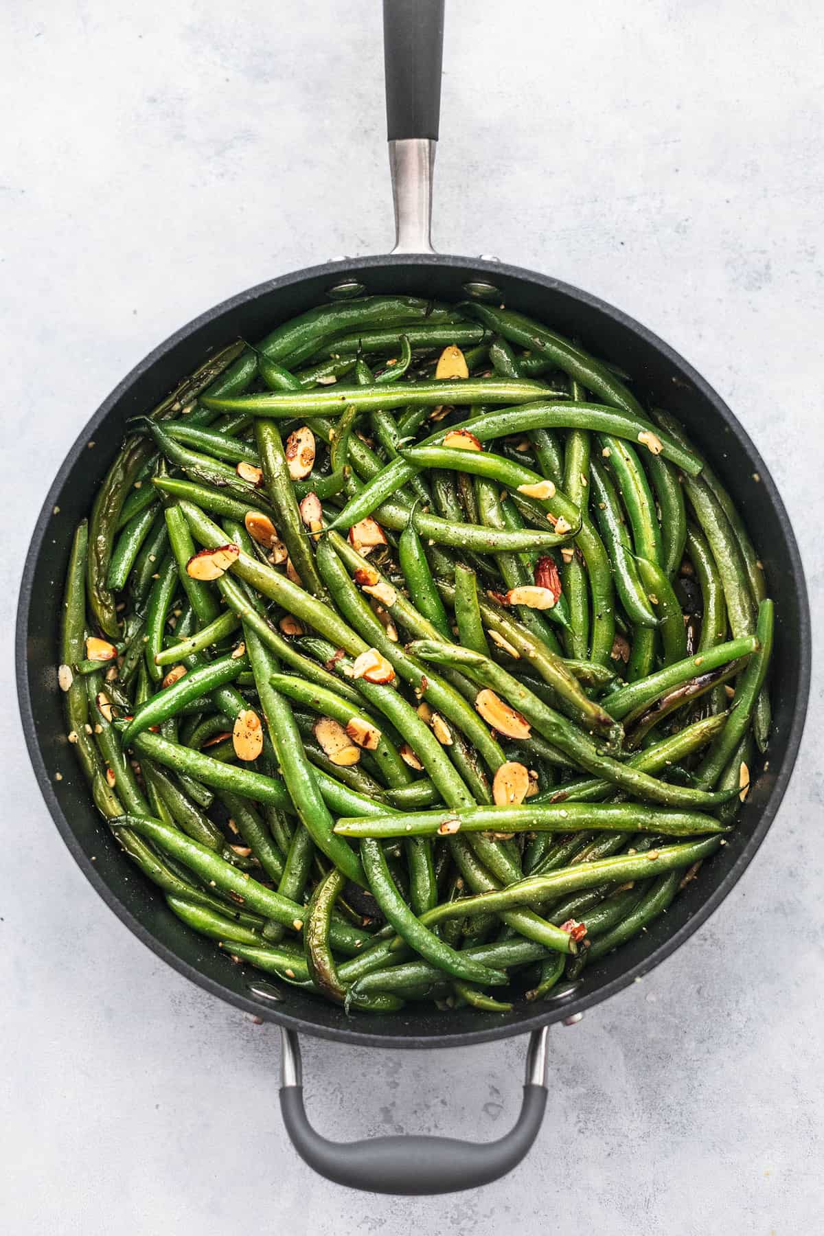 top view of sautéed green beans with garlic and almonds in a skillet.