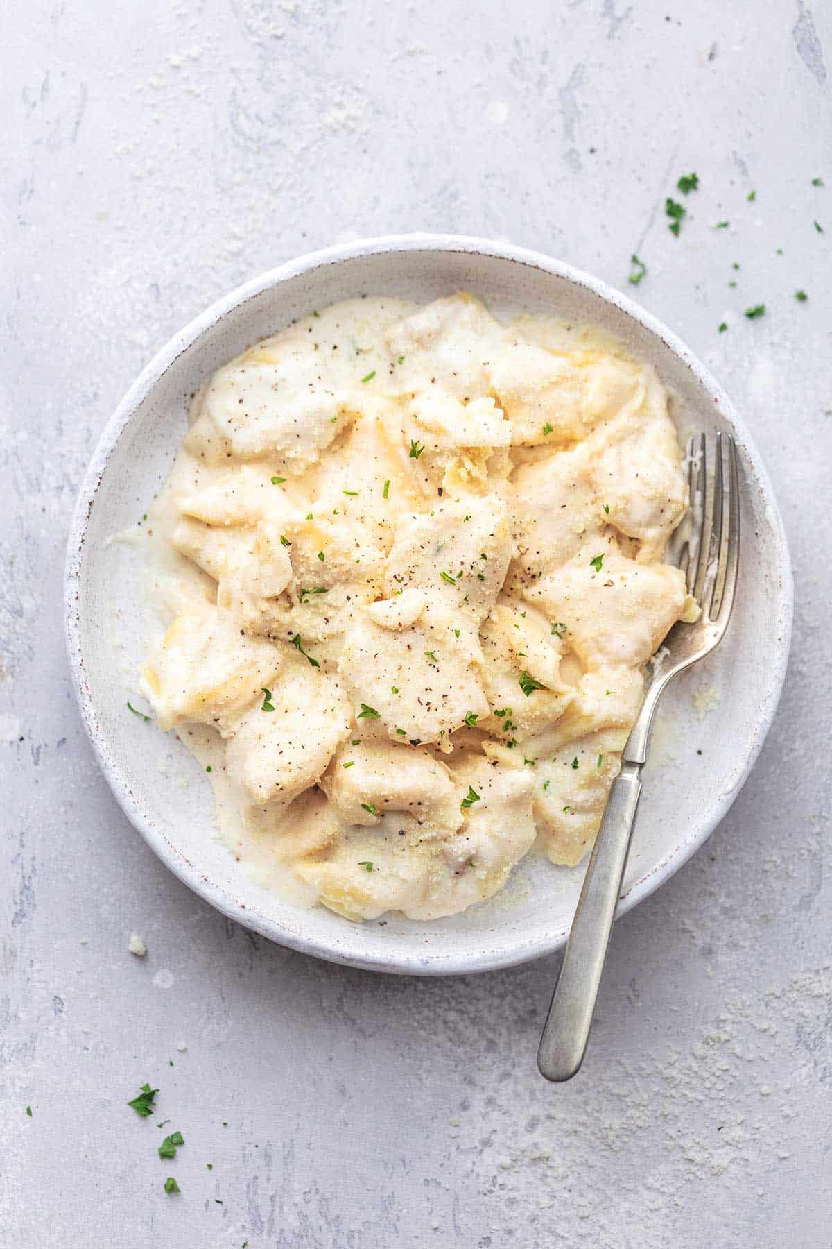 top view of tortellini alfredo with a fork on a plate.