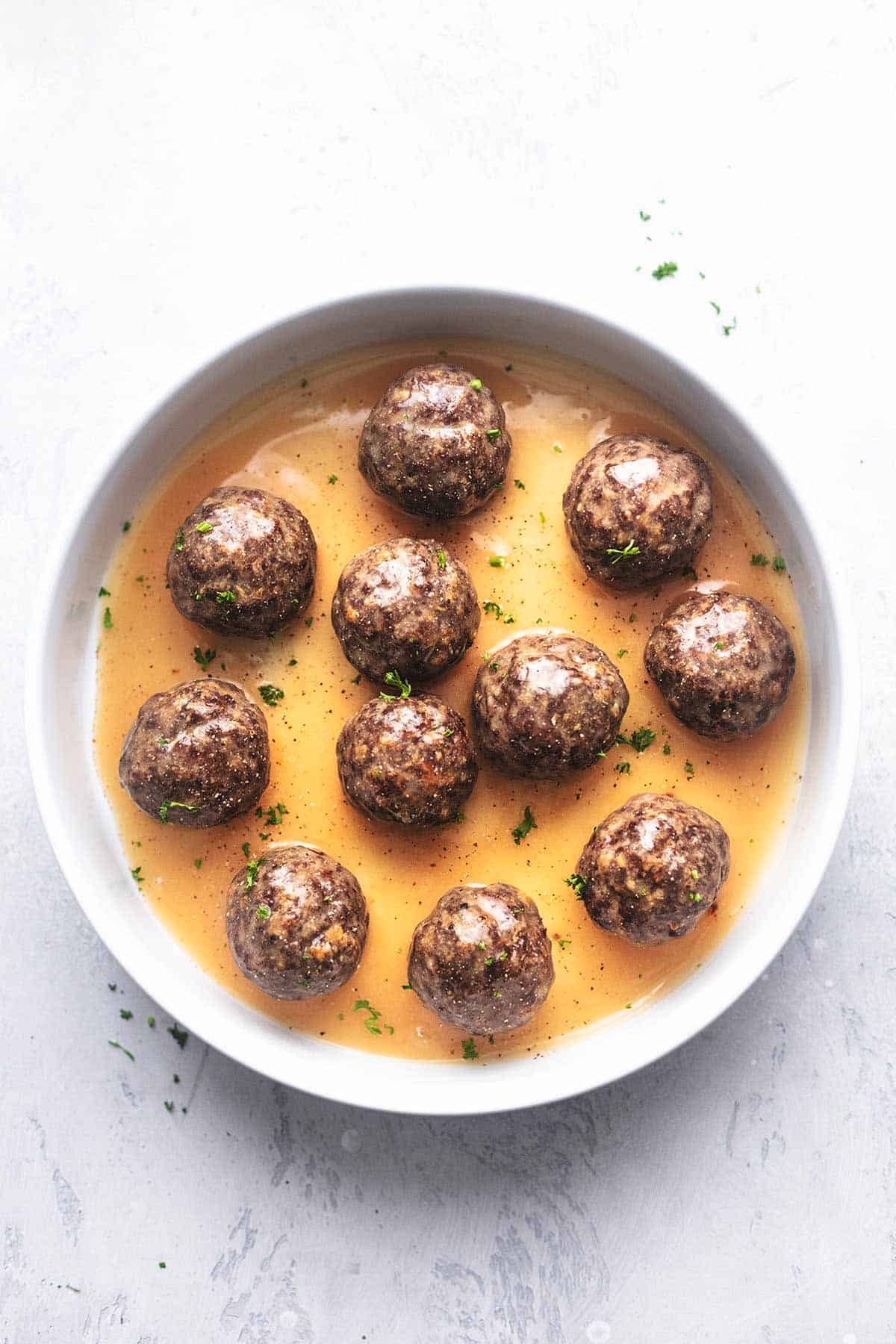 top view of baked meatballs with gravy on a plate.