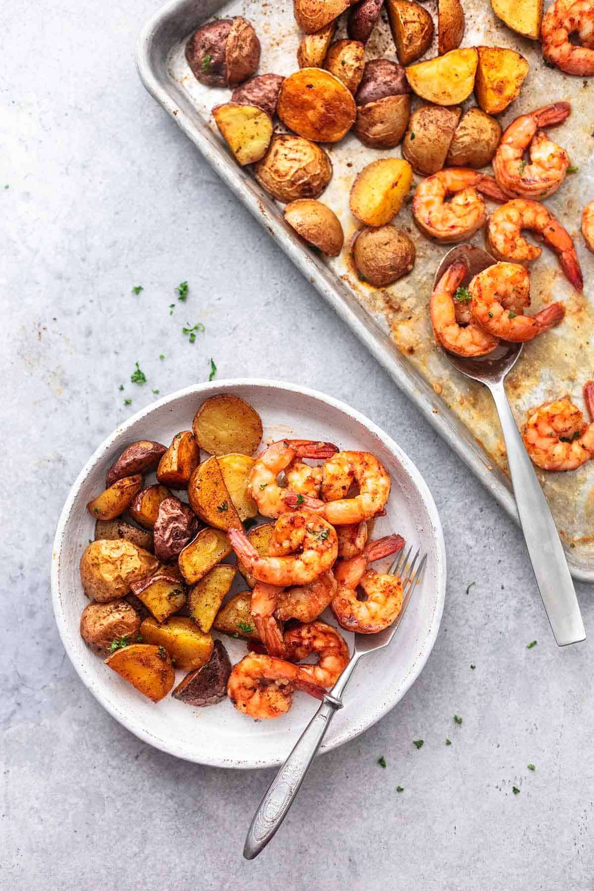 top view of sheet pan cajun shrimp and potatoes on a plate and on a sheet pan on the side.
