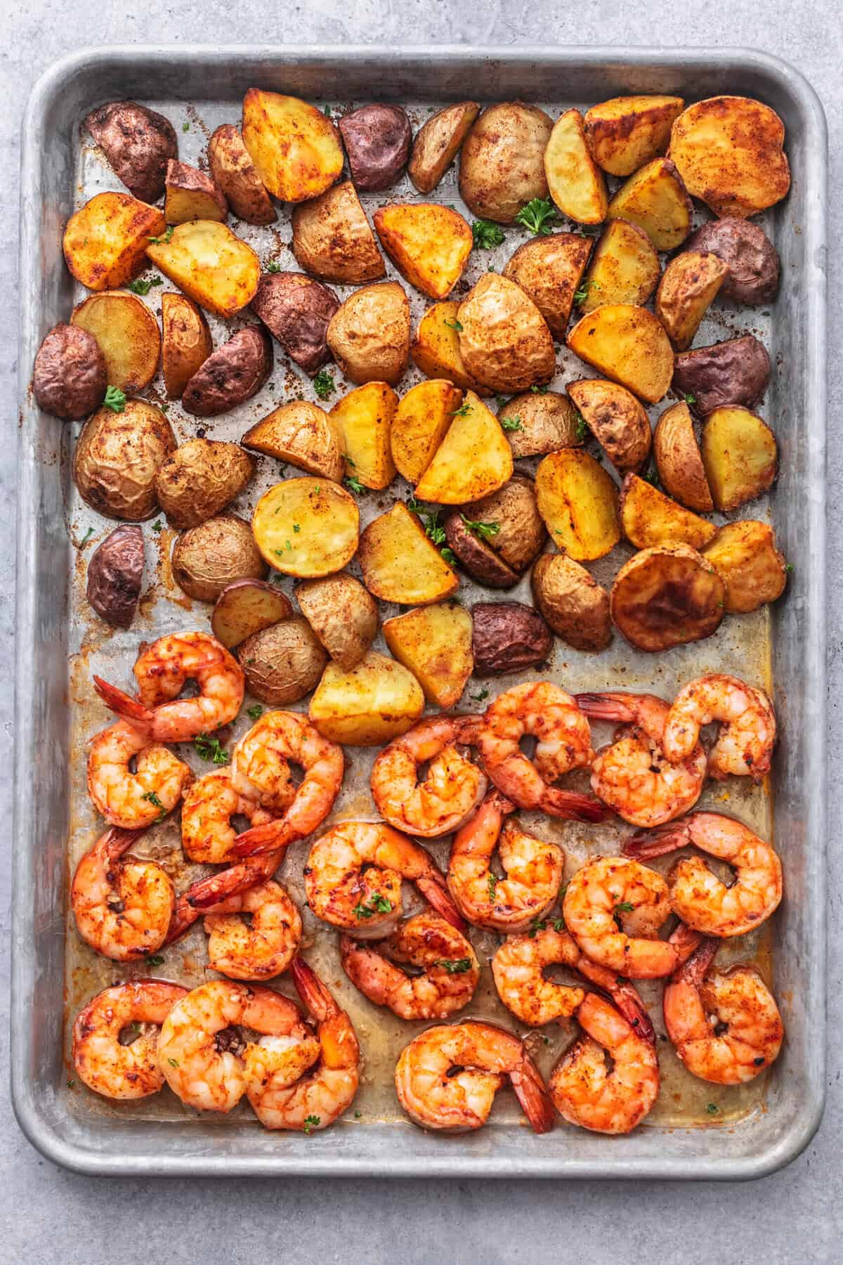 cooked shrimp and potatoes on a sheet pan.