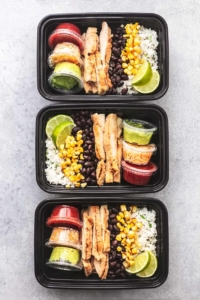 three chicken burrito bowls in meal prep containers