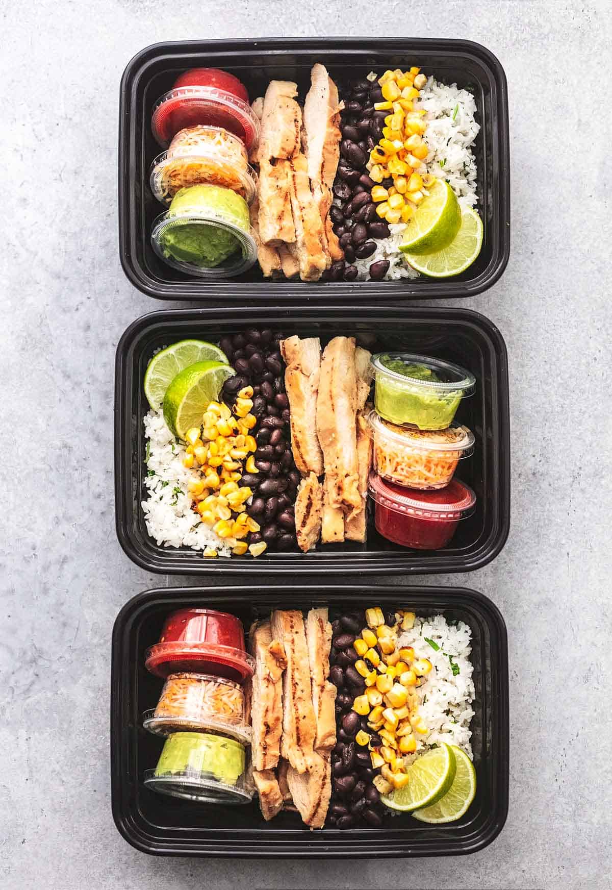 top view of three chicken burrito bowls in meal prep containers.