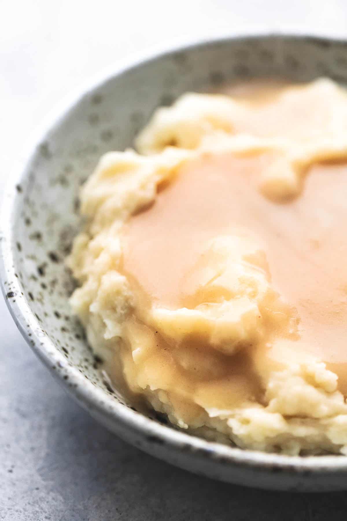 close up of chicken gravy on mashed potatoes in a bowl.