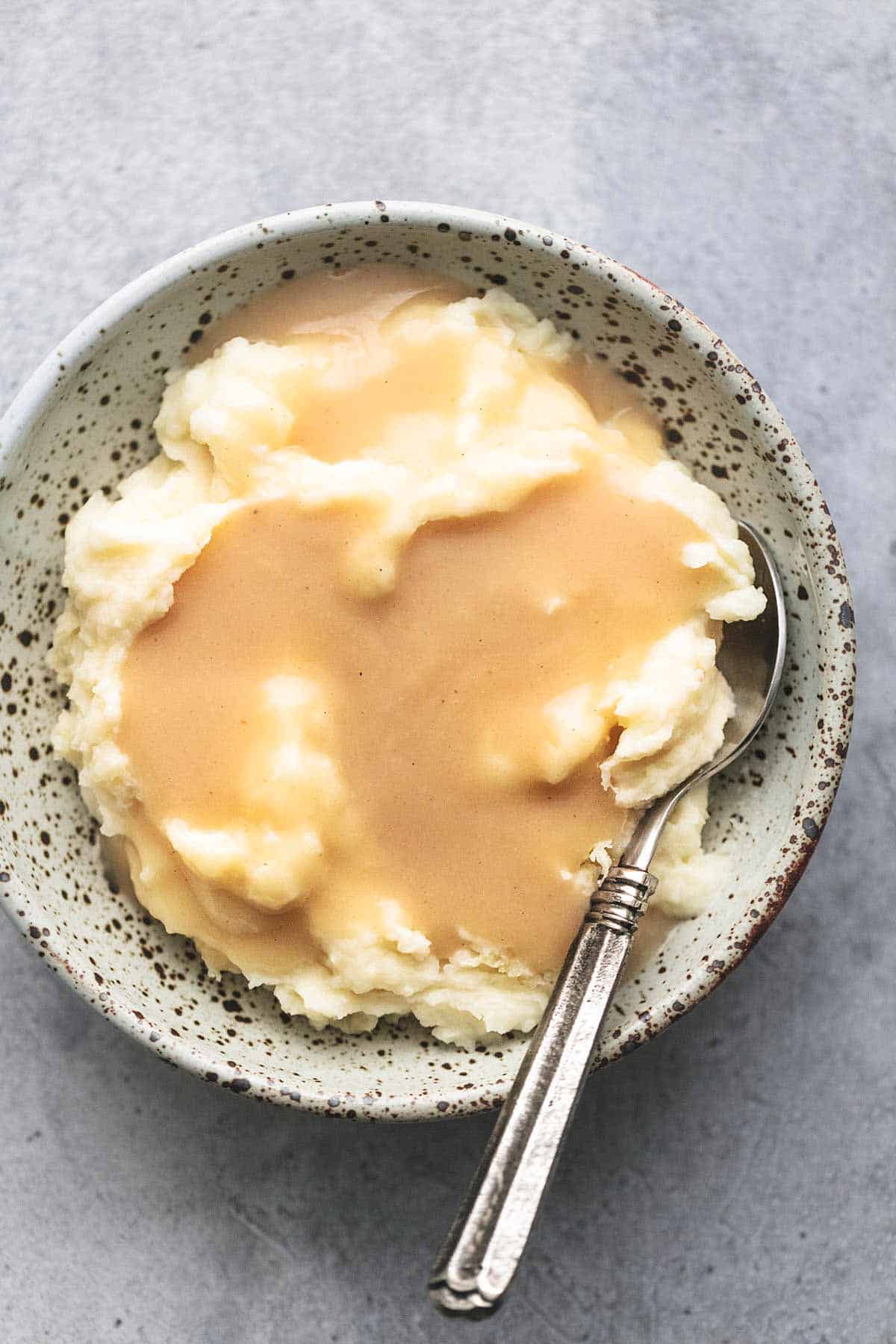 chicken gravy over mashed potatoes in a bowl with a spoon overhead