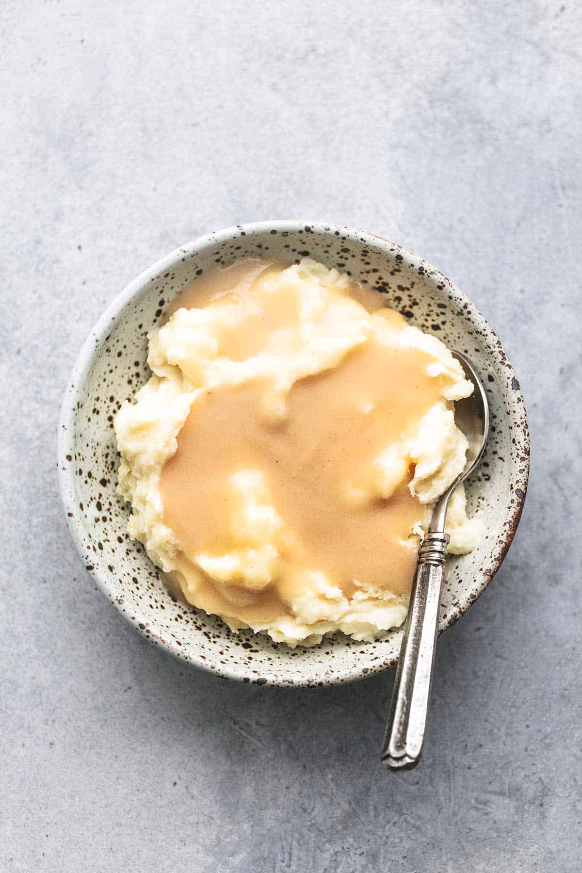 top view of chicken gravy on mashed potatoes in a bowl with a spoon.