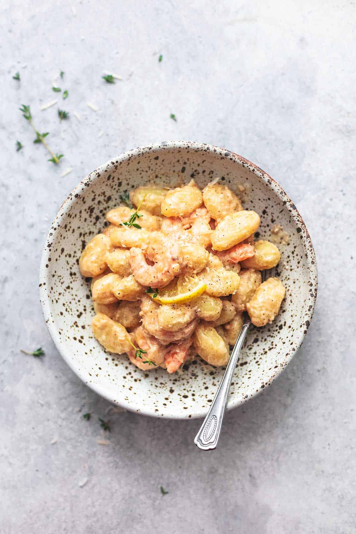 top view of creamy lemon garlic shrimp and gnocchi in a bowl with a spoon.