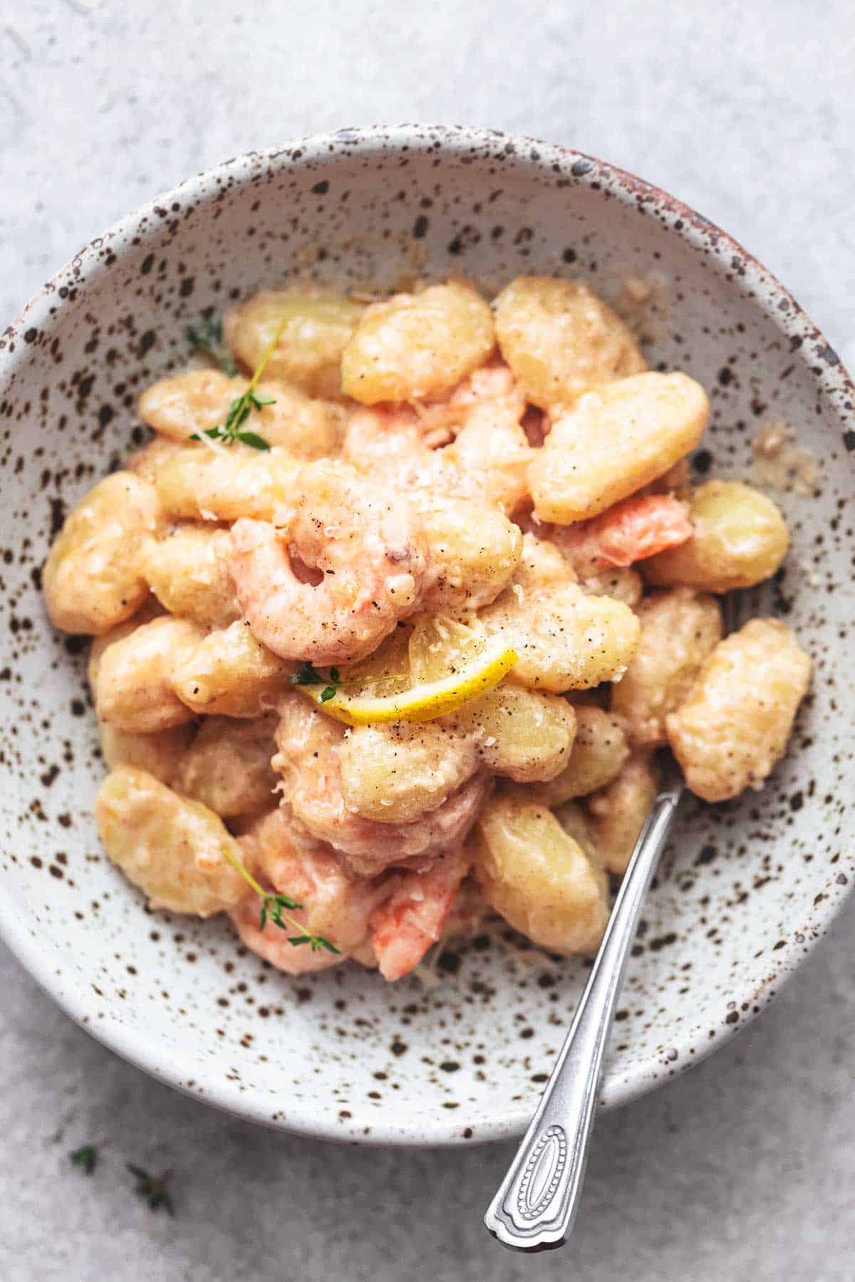 close up top view of creamy lemon garlic shrimp and gnocchi in a bowl with a fork.