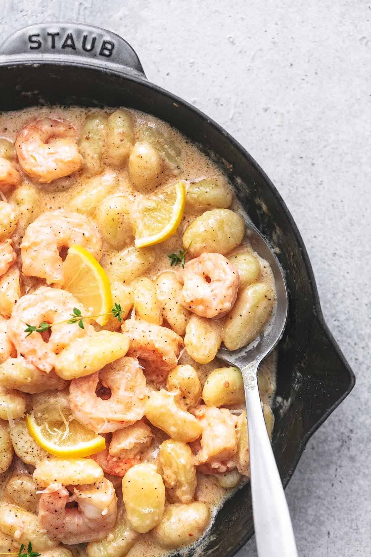 close up top view of creamy lemon garlic shrimp and gnocchi in a skillet with a serving spoon.