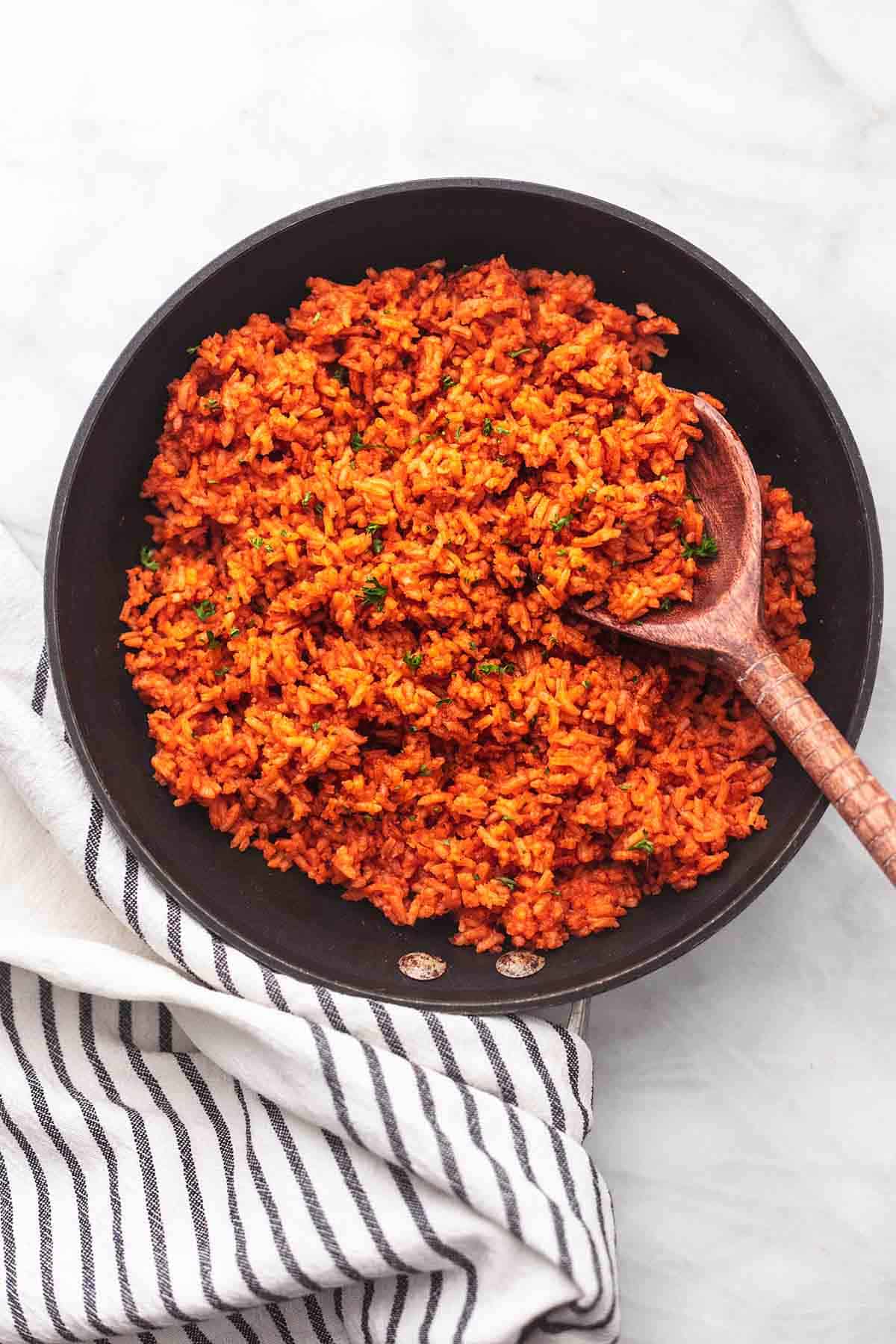 spanish rice in a skillet with a serving spoon