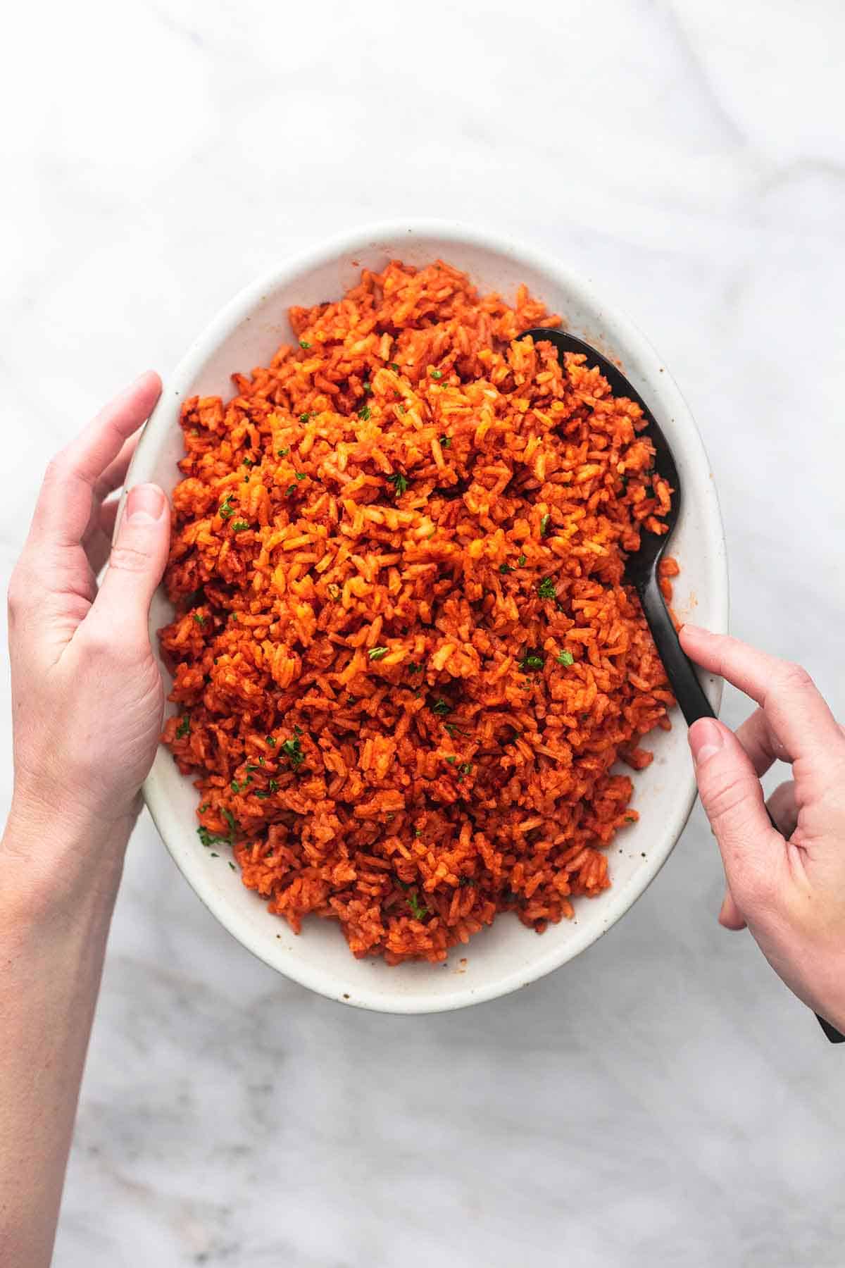 hands holding a plate with spanish rice