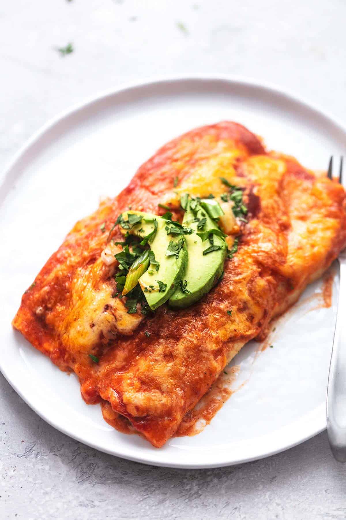 enchiladas on a white plate with a fork