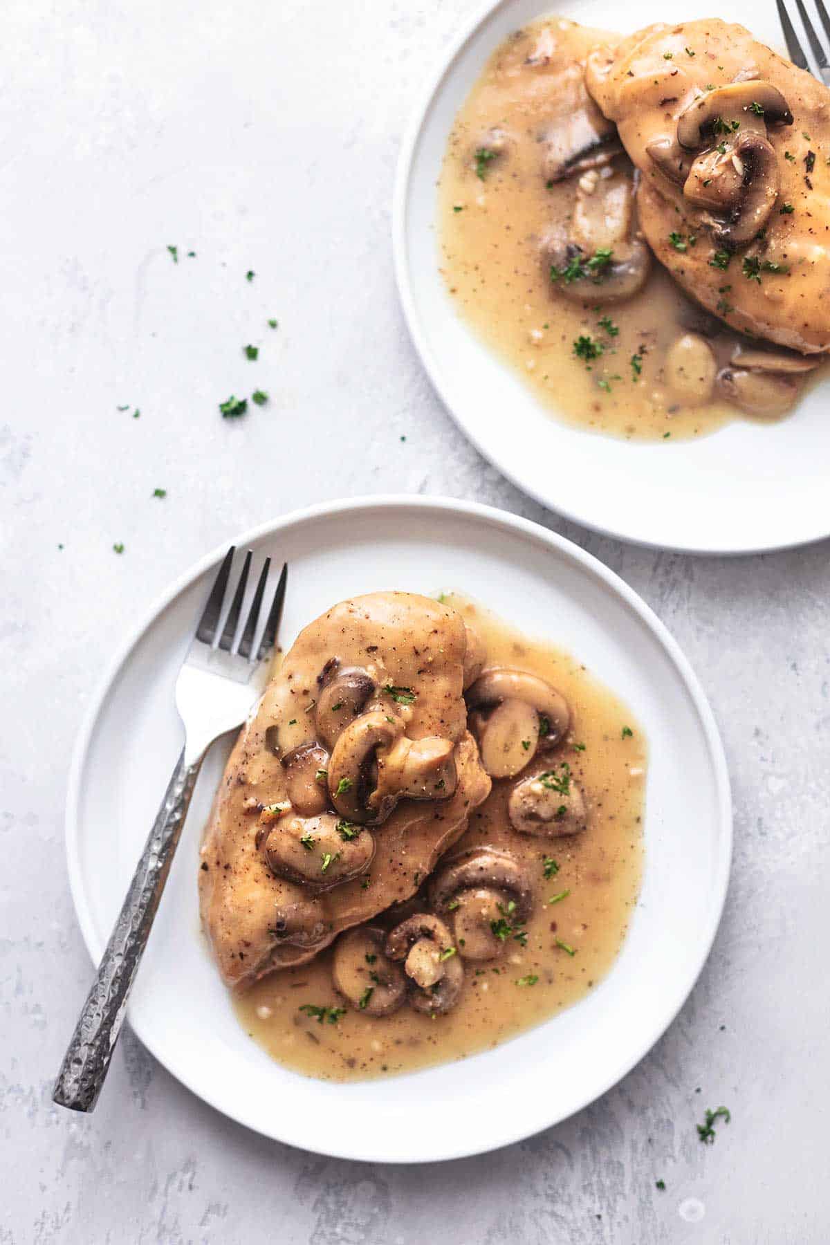 chicken with gravy and mushrooms on a white plate with a fork