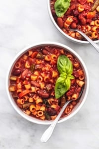 bminestrone soup in two bowls on a marble surface