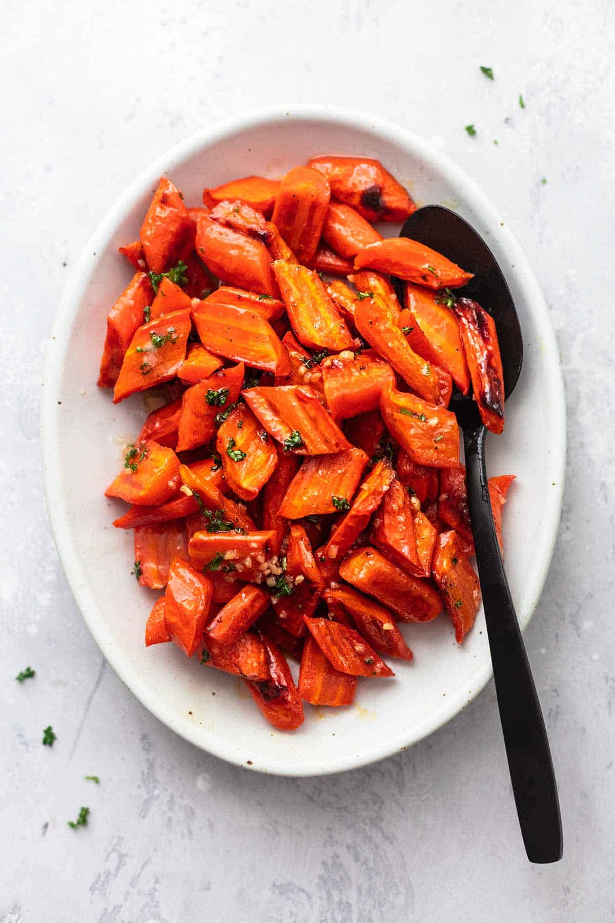 top view of roasted honey garlic glazed carrots on a serving platter with a serving spoon.