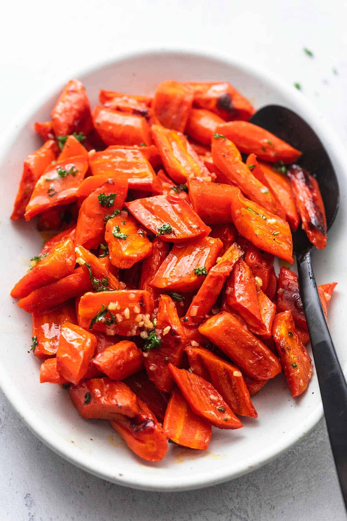 cooked carrots on a platter with a serving spoon