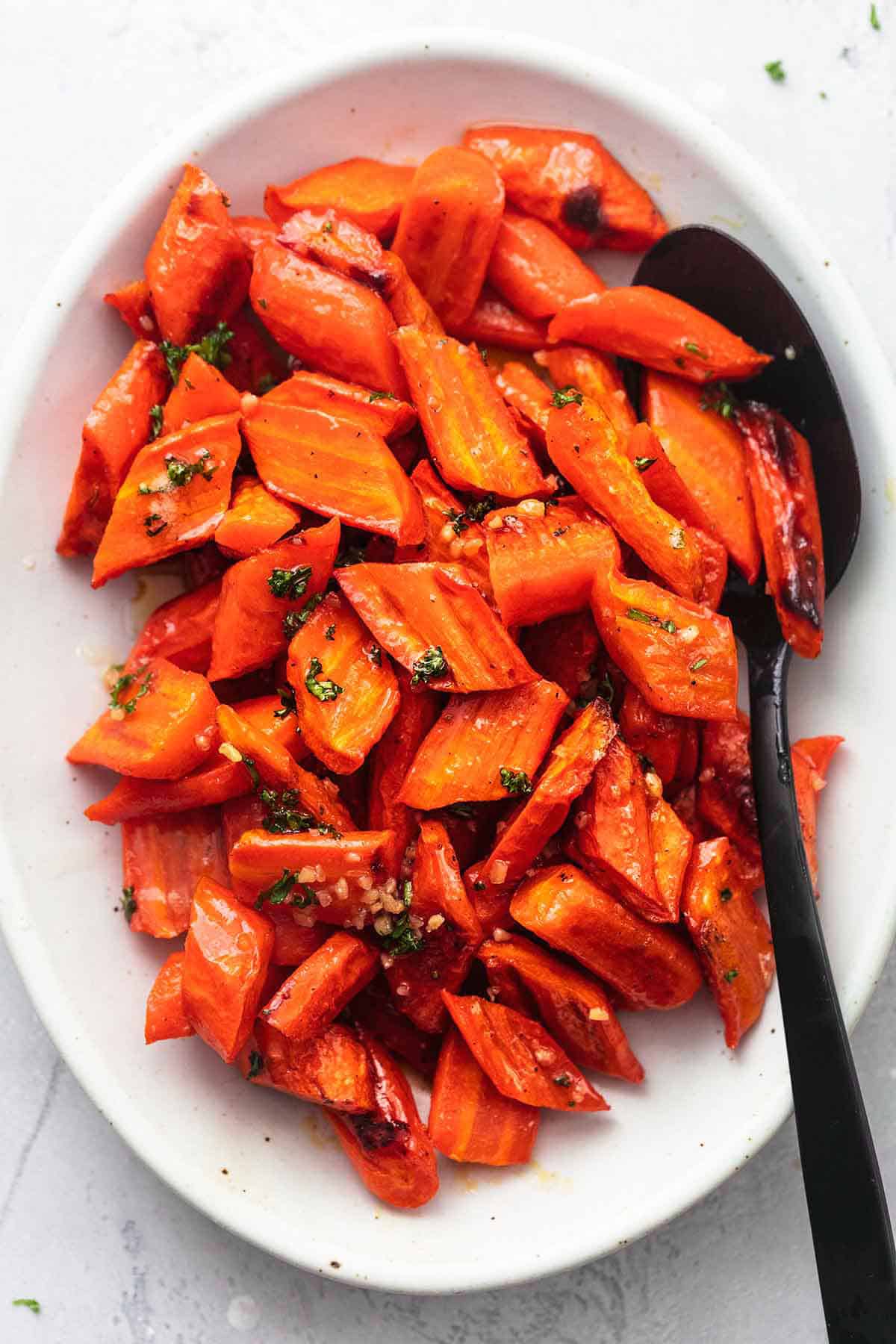 top view o f roasted honey garlic glazed carrots on a serving platter with a serving spoon.