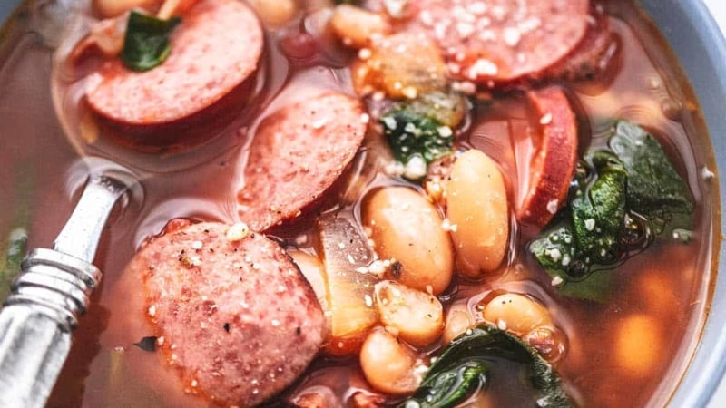 up close white bean and sausage soup with spinach