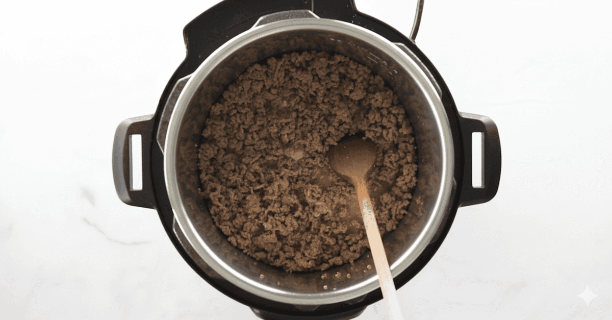 Cooked ground beef with wooden spoon in instant pot.