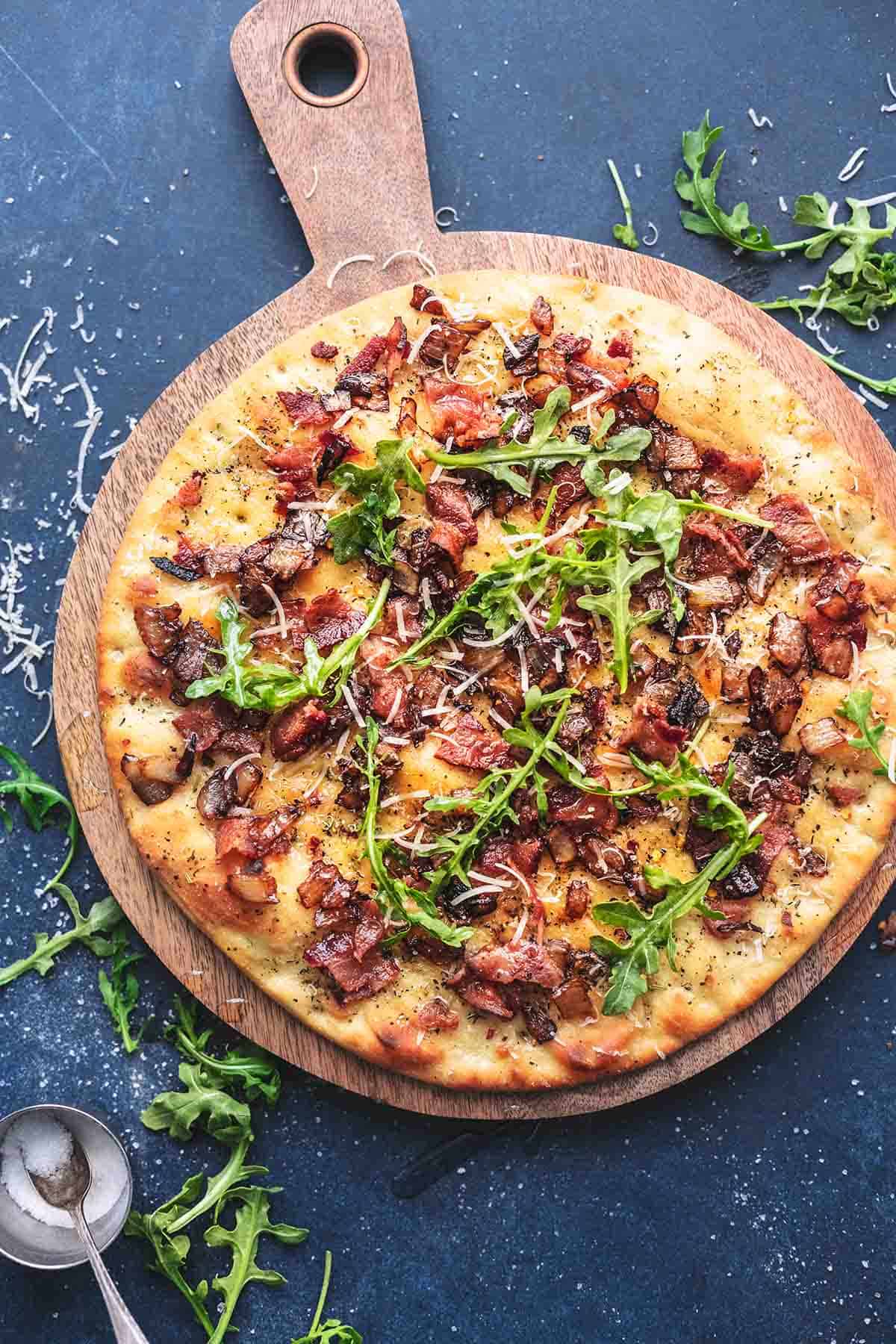 top view of caramelized onion and bacon flatbread on a wooden serving board.