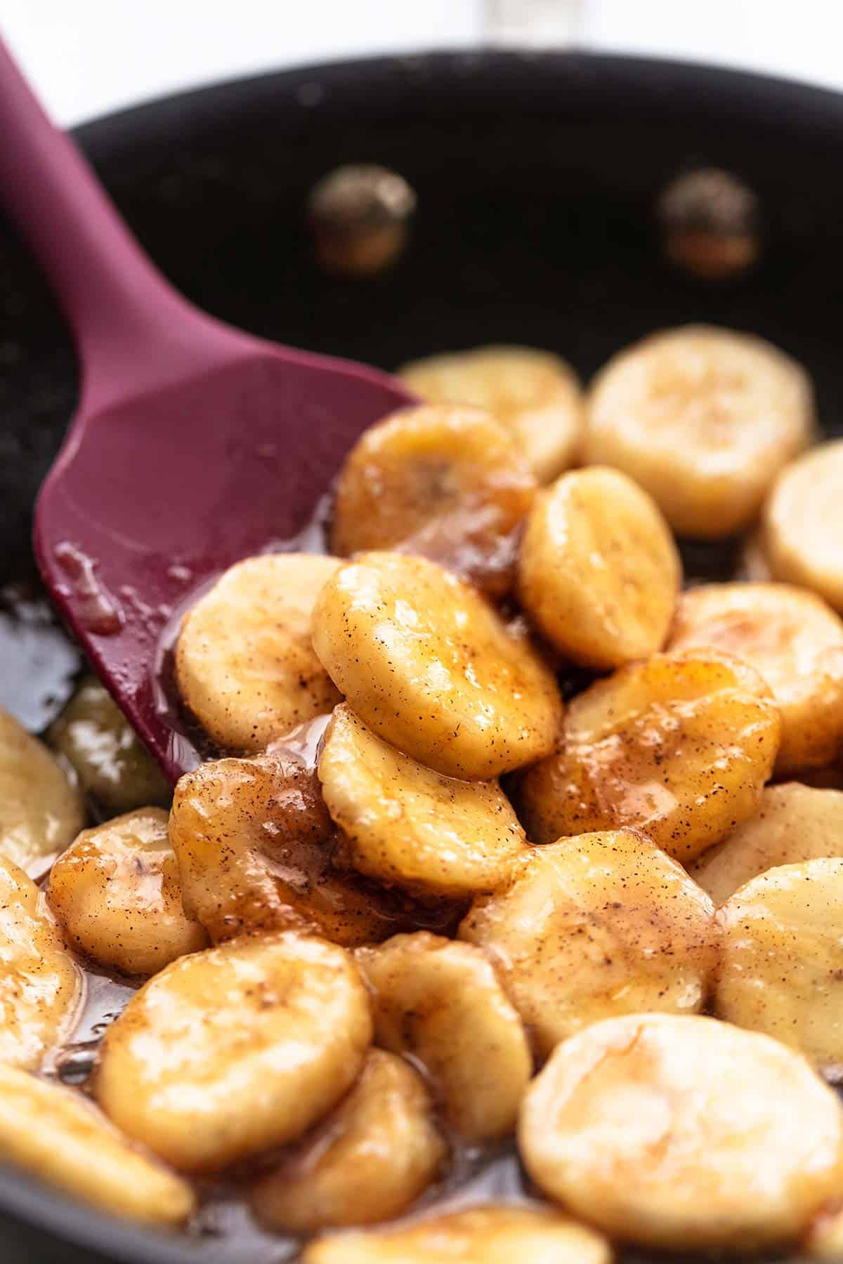 close up of caramelized bananas in a skillet with a spatula.