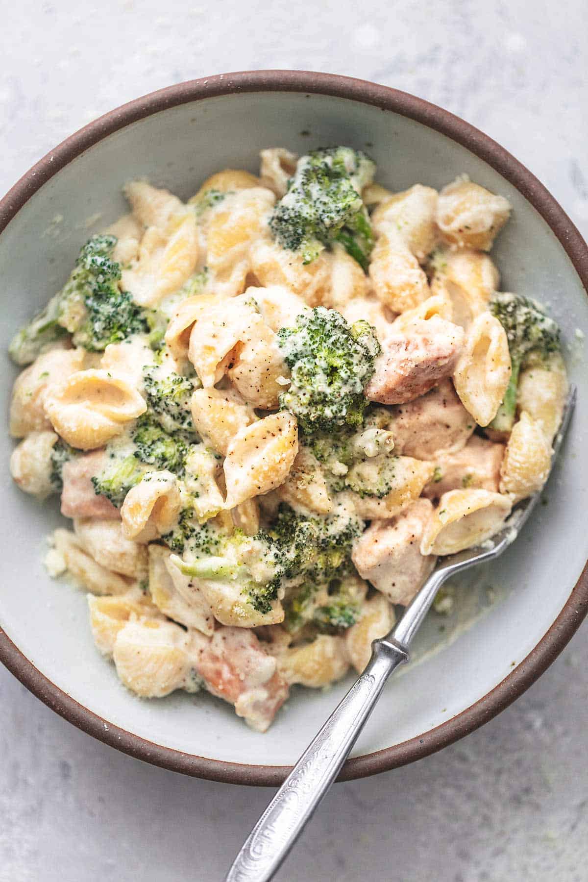 top view of chicken alfredo with broccoli with a fork in a bowl.