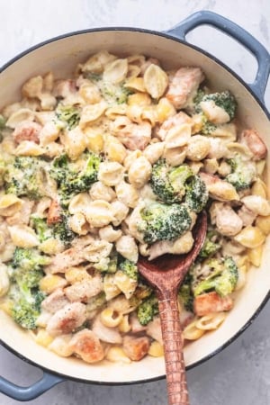 chicken alfredo pasta shells with broccoli and serving spoon in skillet