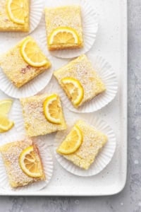 lemon bars on cupcake liners on a baking sheet overhead