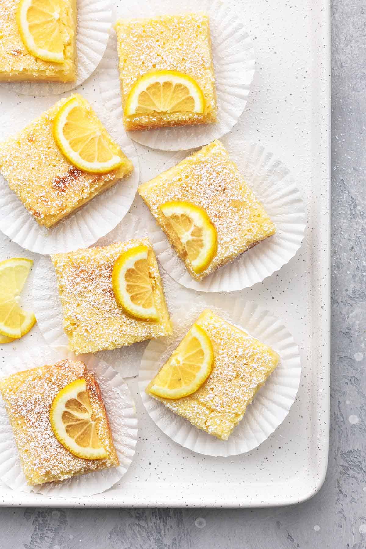 lemon bars on cupcake liners on a baking sheet overhead