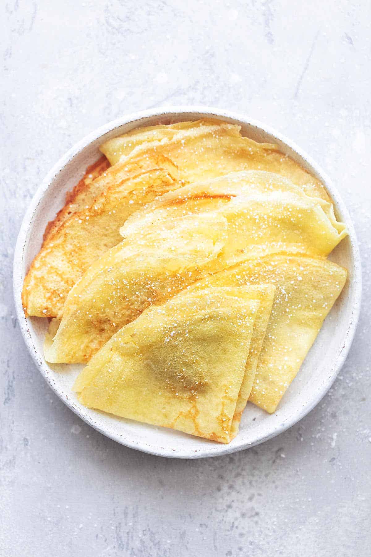 top view of folded crepes on a white plate.