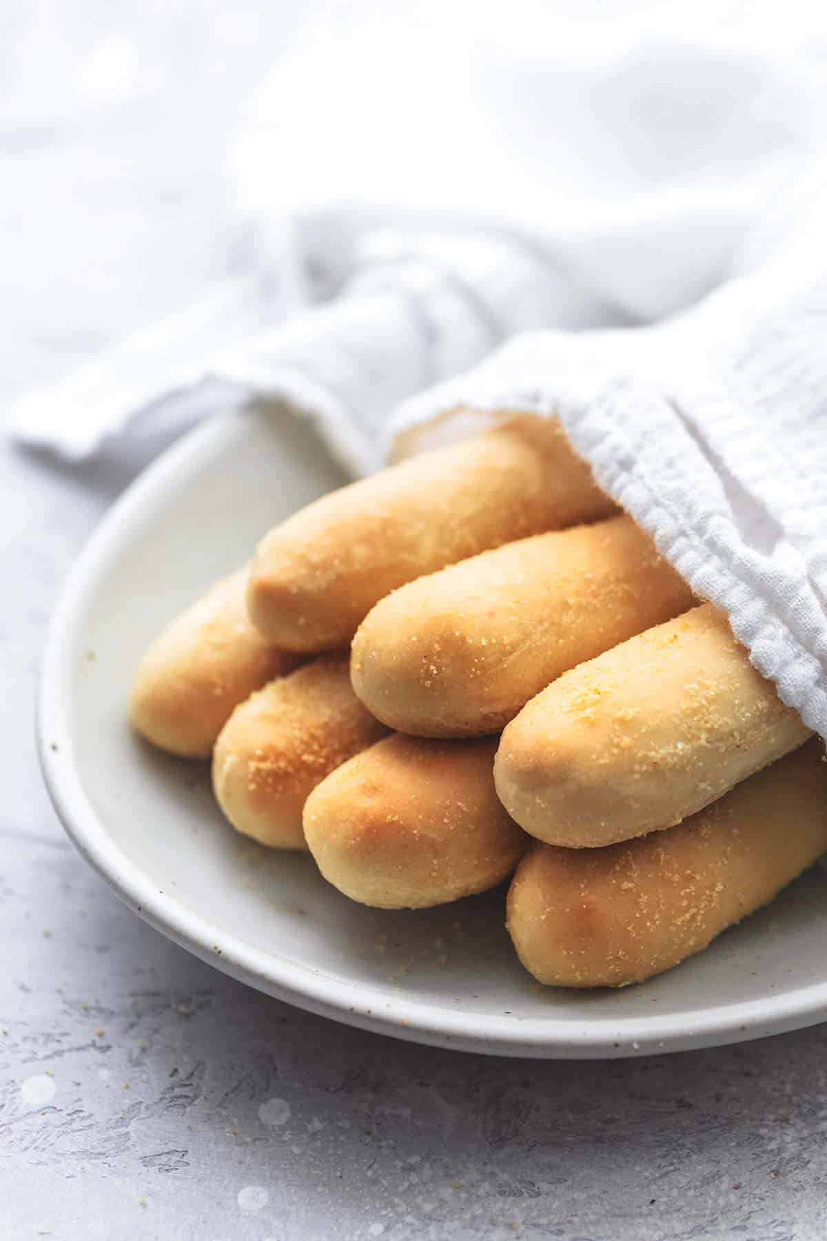 Olive Garden breadsticks partly covered in a napkin on a plate.