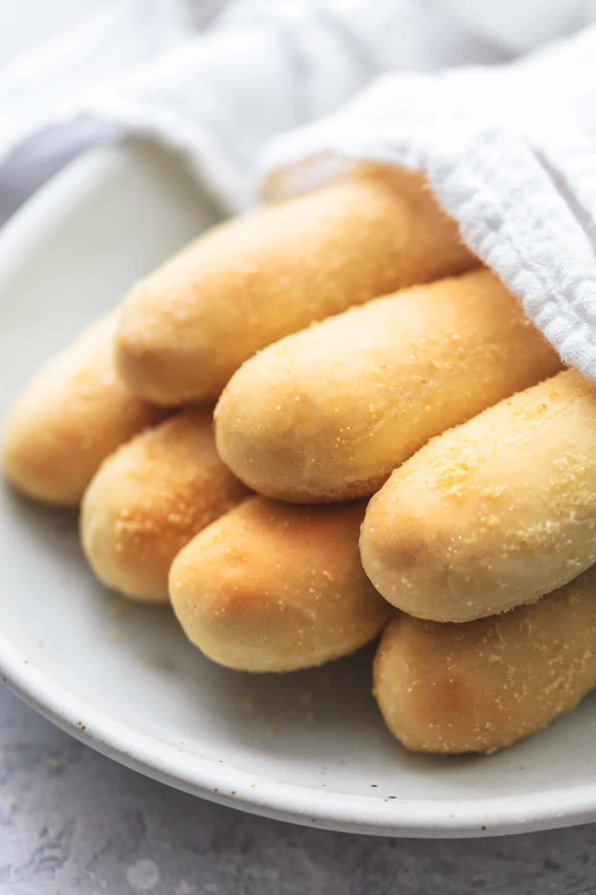 close up of Olive Garden breadsticks partly covered with a napkin on a plate.