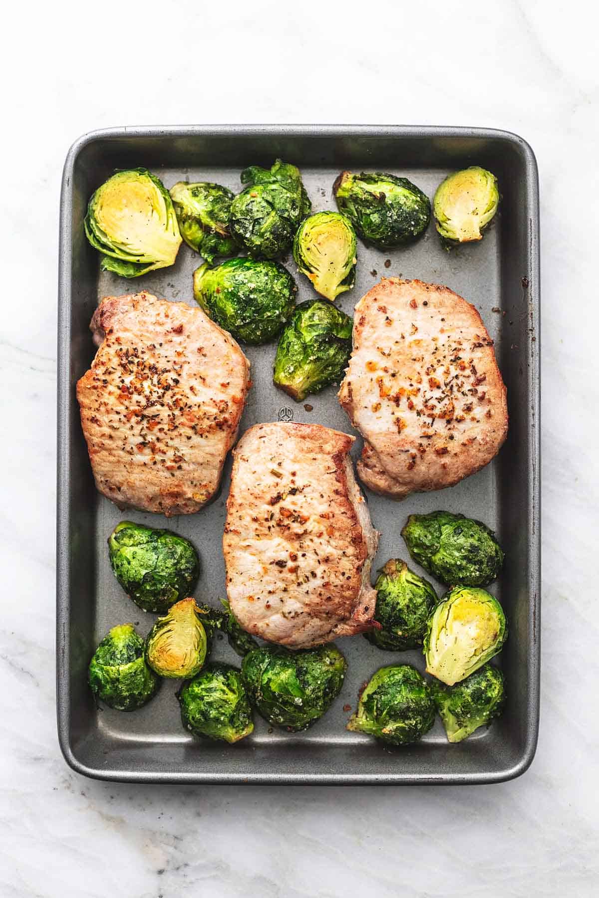 top view of pork chops and brussels sprouts on a baking sheet.