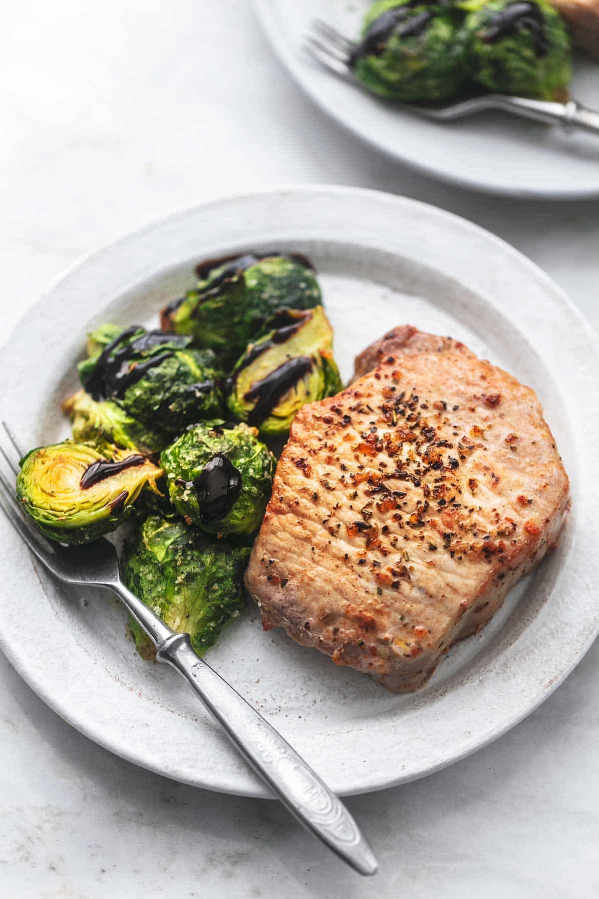 up close pork chop and brussels sprouts on a plate