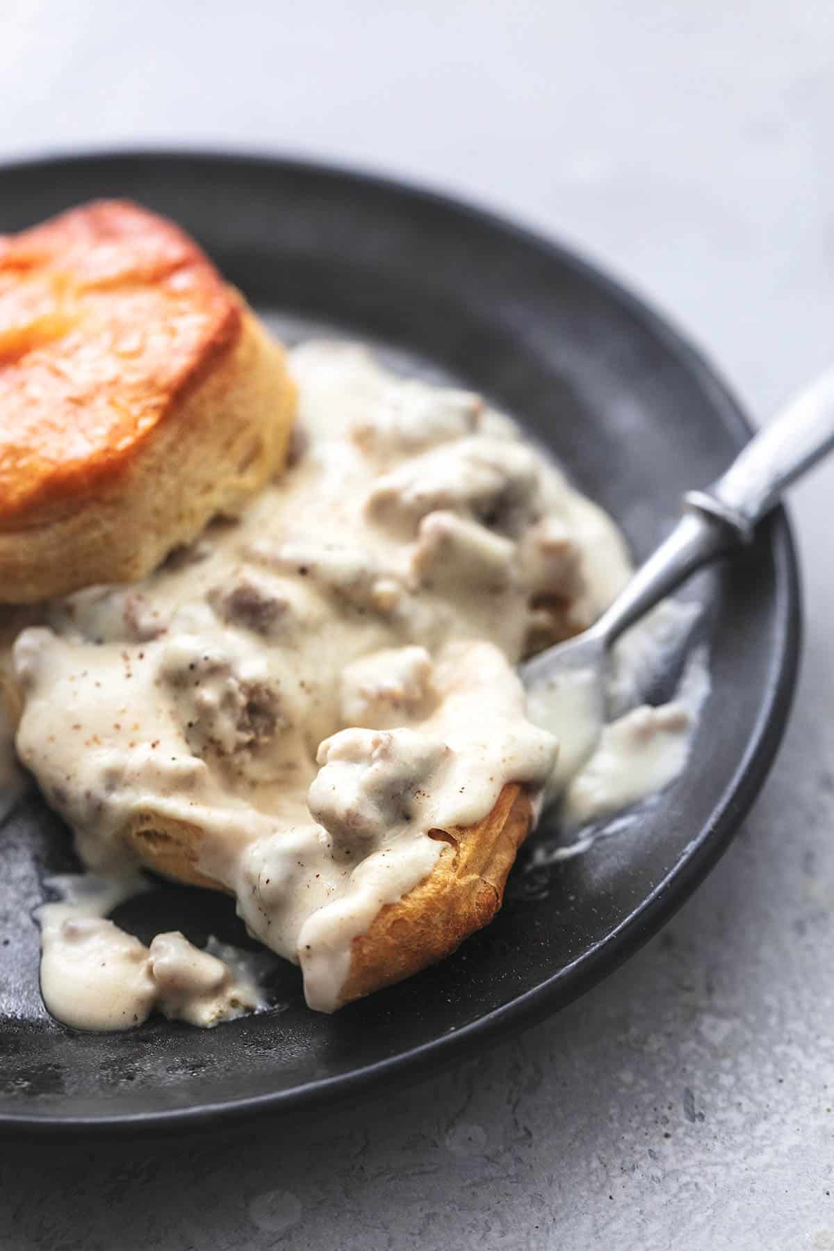 up close biscuits and sausage gravy with fork on plate