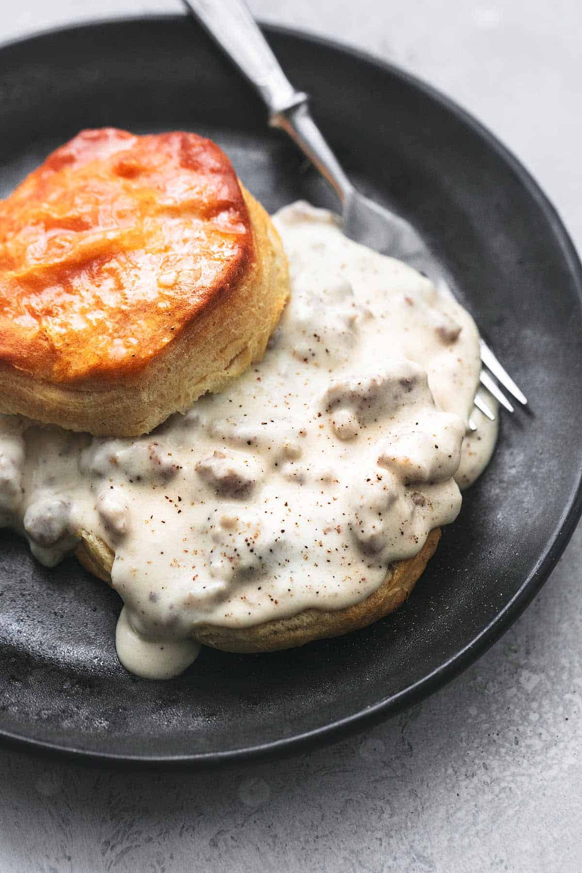  biscuits and sausage gravy with fork on plate