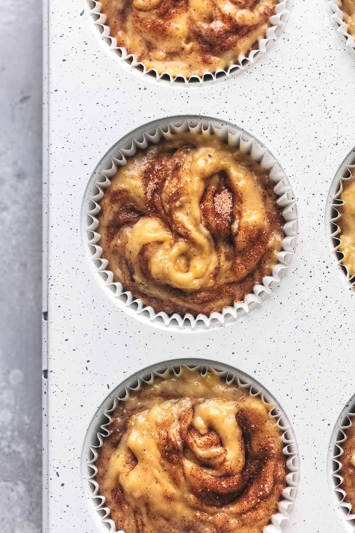 close up top view of cinnamon swirl banana muffins unbaked in a muffin tin.