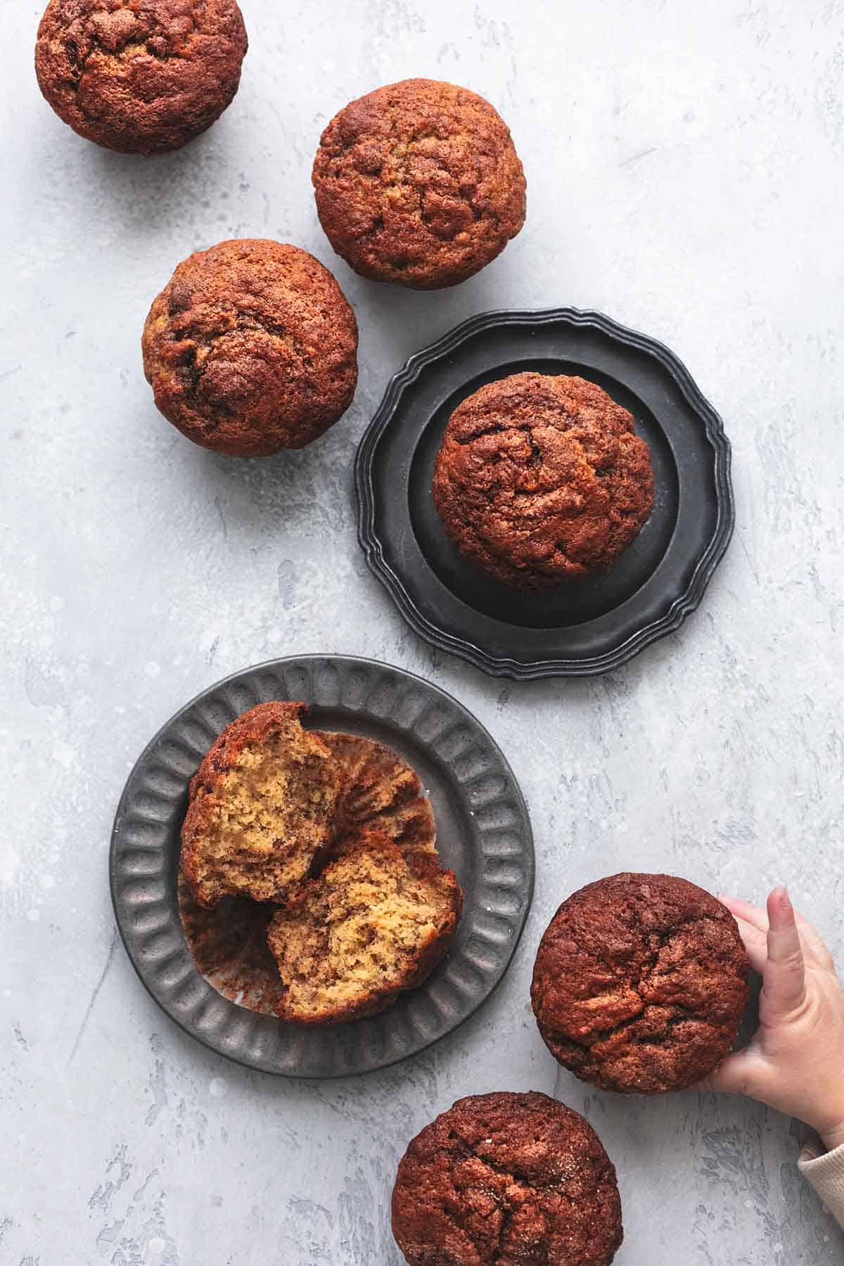 top view of cinnamon swirl banana muffins on a table and on plates.