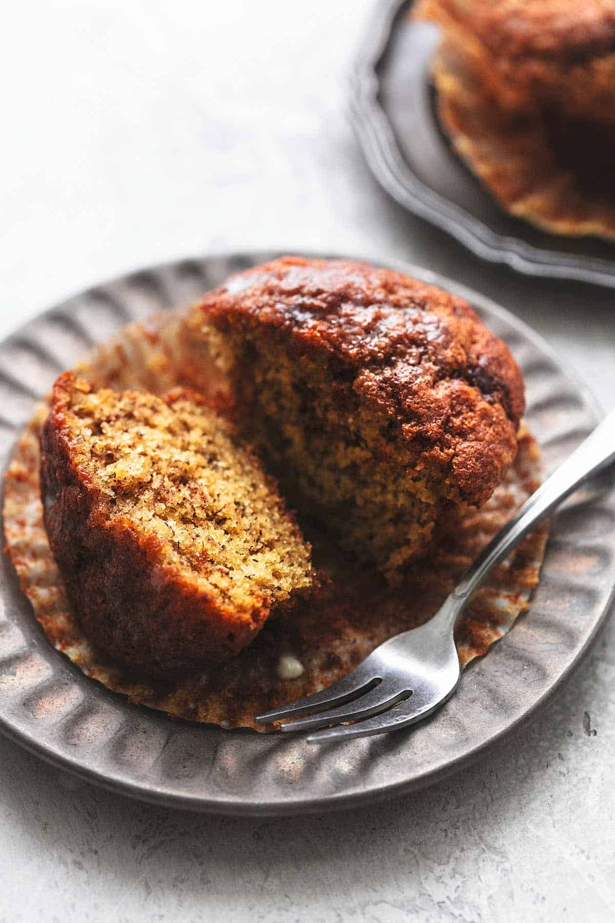 a cinnamon swirl banana muffin sliced in half with butter on a plate with a fork.