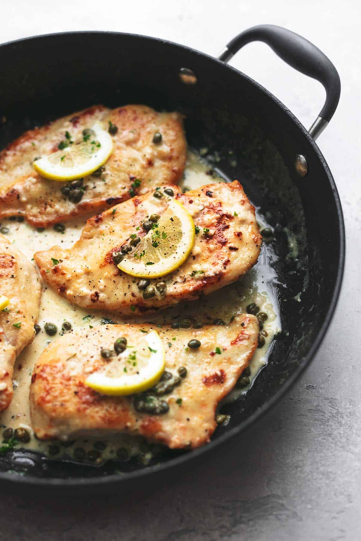 close up of creamy lemon chicken piccata in a skillet.