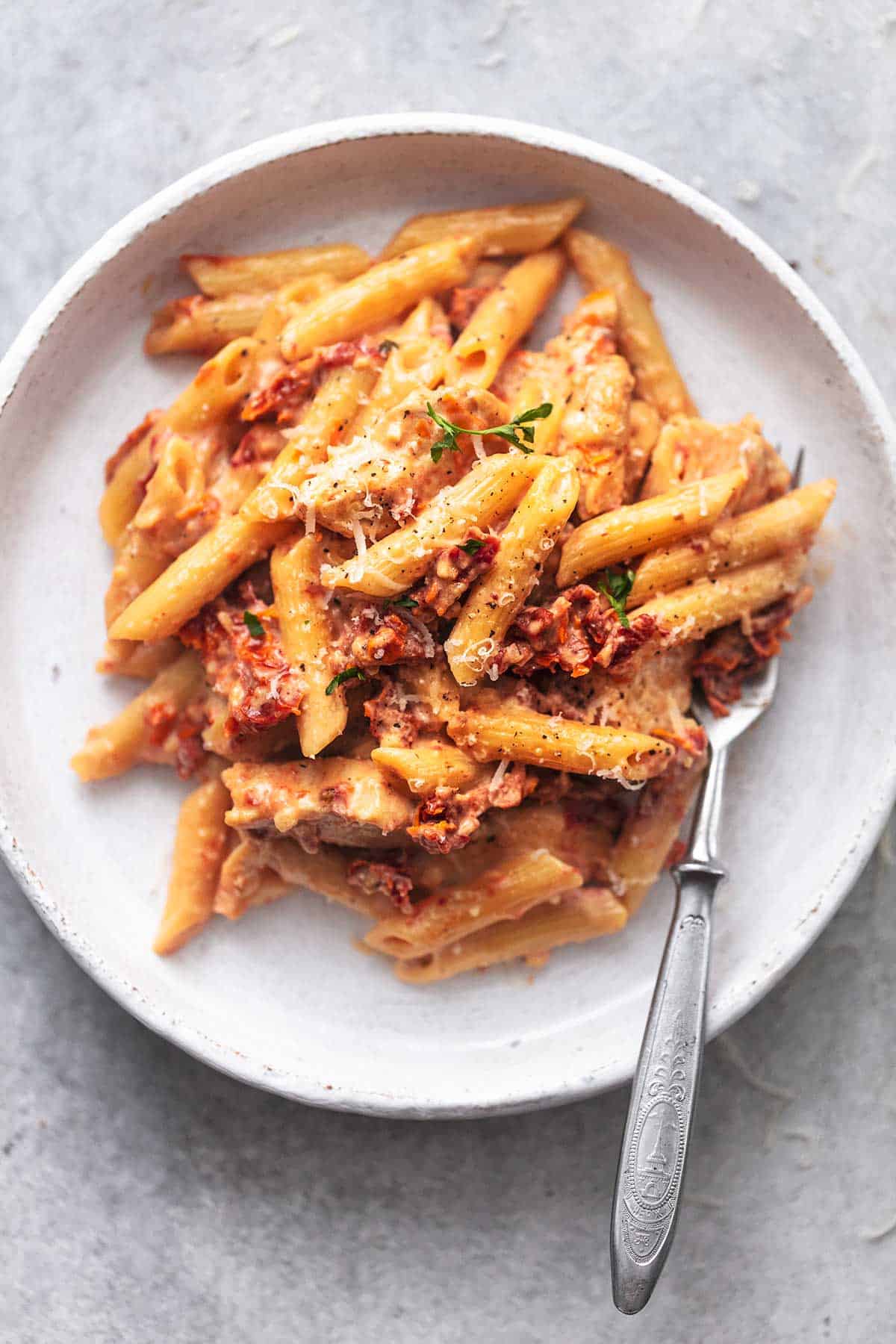 up close overhead sun dried tomato pasta on white plate with fork