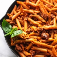 penne noodles with fresh basil and tomato sauce in skillet
