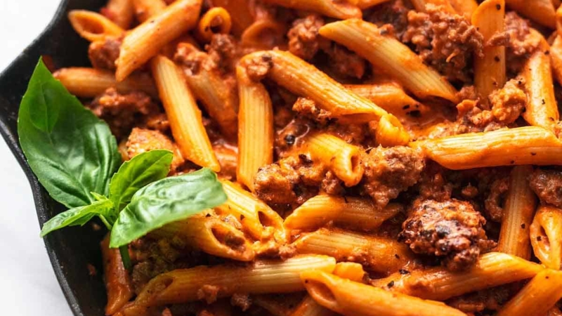 penne noodles with fresh basil and tomato sauce in skillet