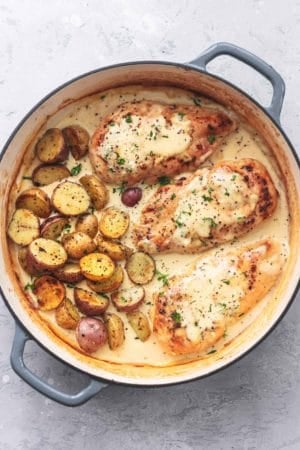 chicken and potatoes with creamy sauce and fresh herbs in a skillet