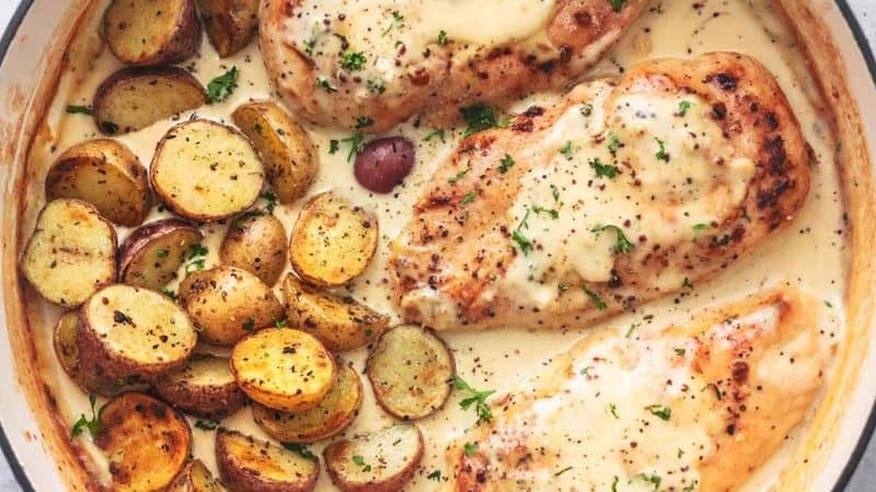 chicken and potatoes with creamy sauce and fresh herbs in a skillet