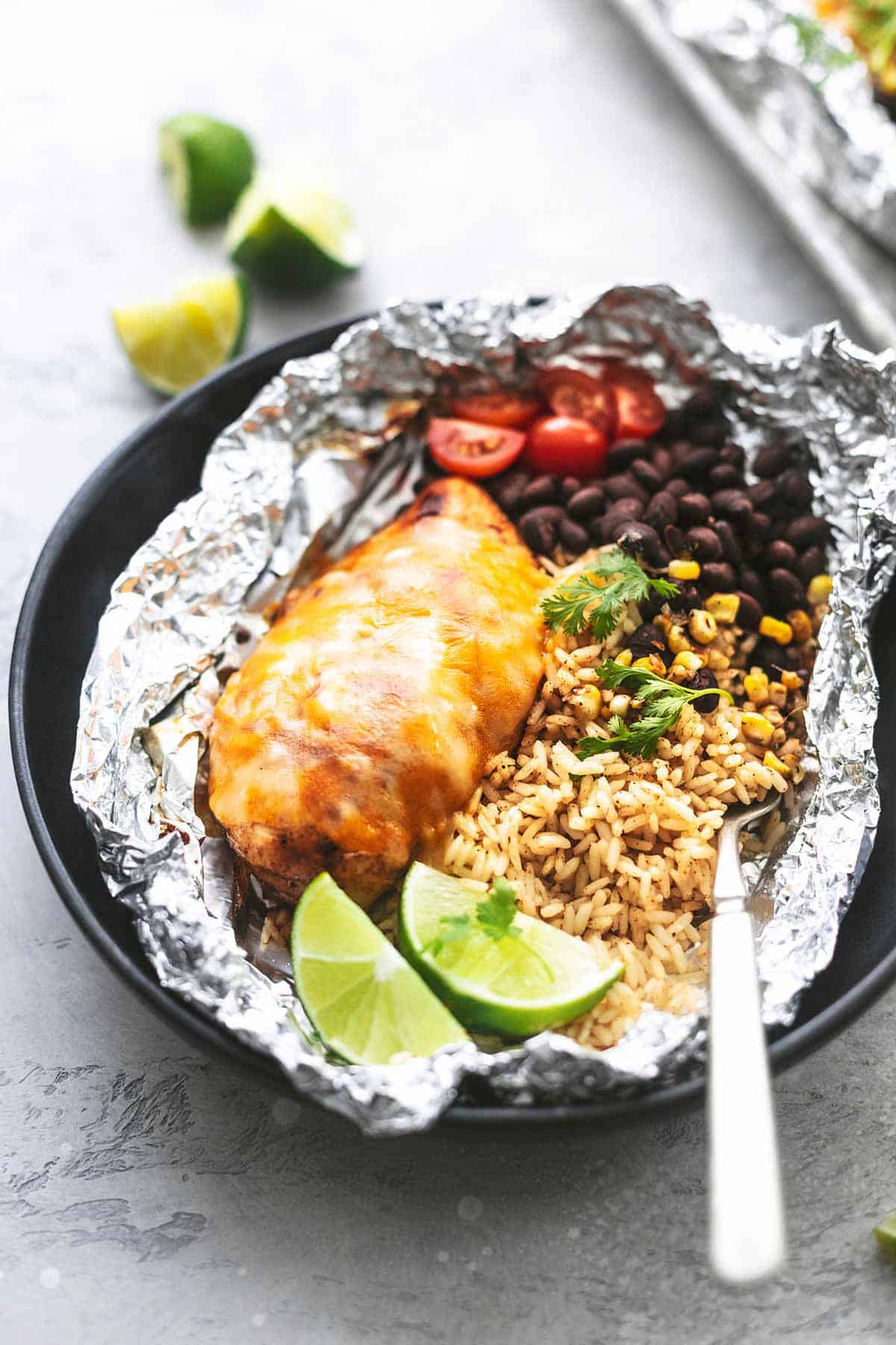 an open fiesta lime chicken and rice foil packs on a plate with a fork.
