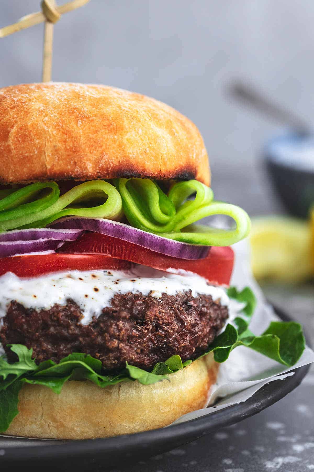 close up of a Greek beef burger with tzatziki sauce.