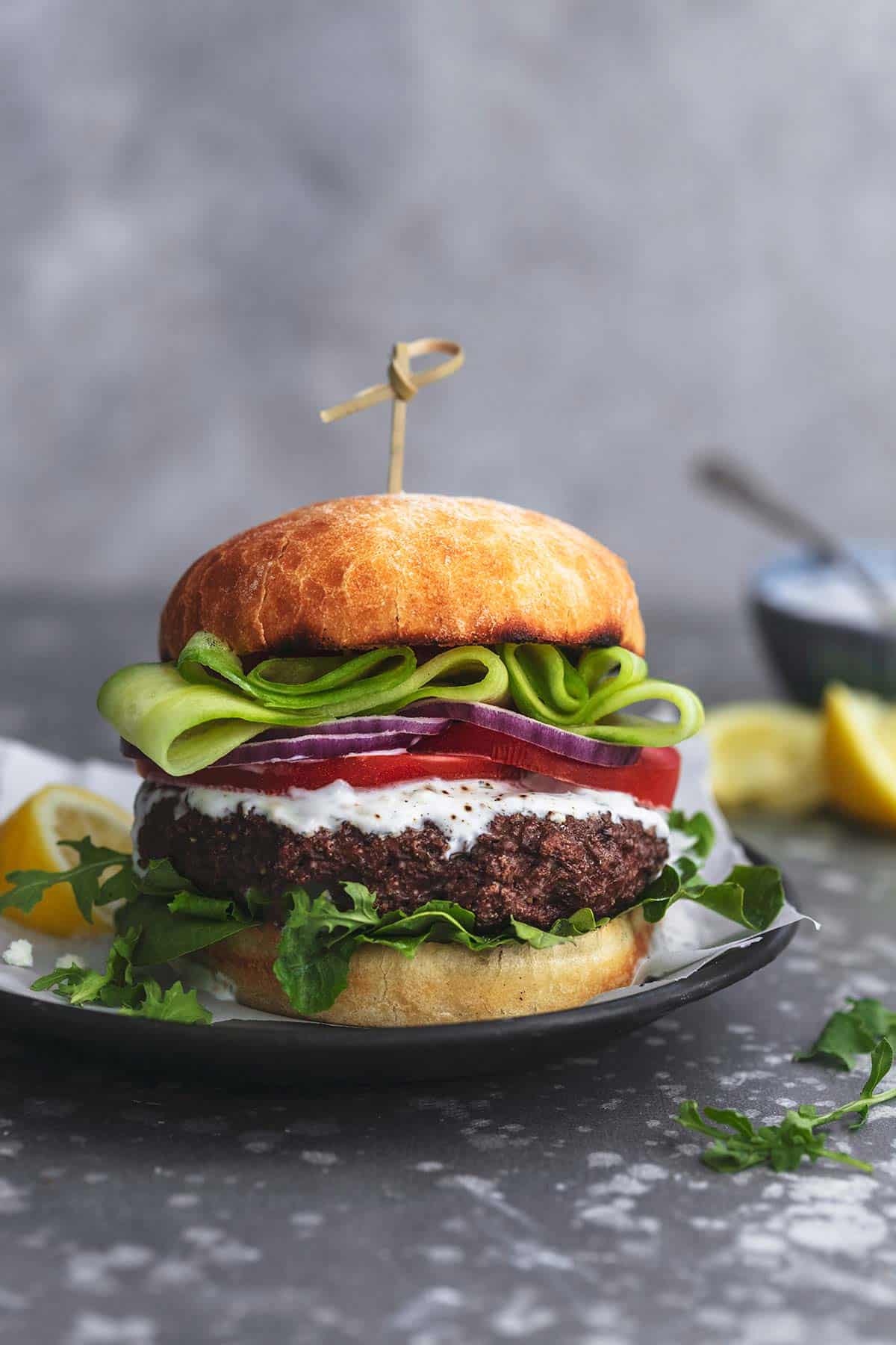 a Greek beef burger with tzatziki sauce on a plate.