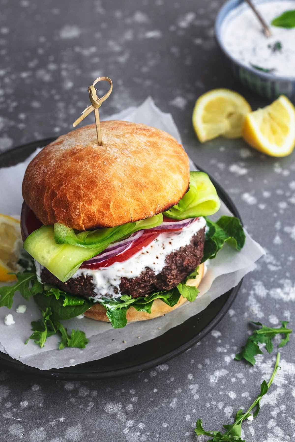 a Greek beef burger with tzatziki sauce on a plate.
