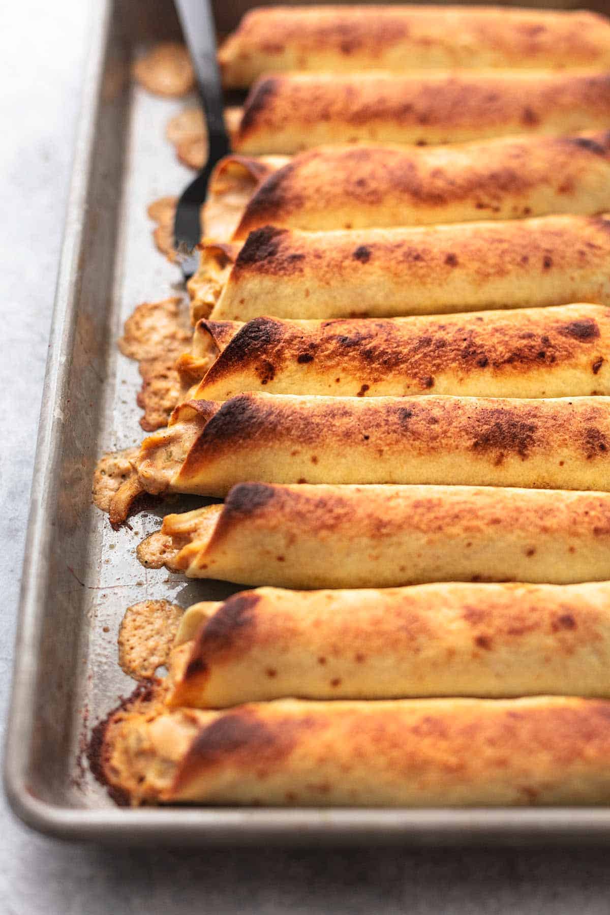 close up of instant pot chicken taquitos on a baking sheet.